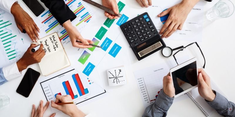 Picture of businessmen's hands on white table with documents, coffee and drafts